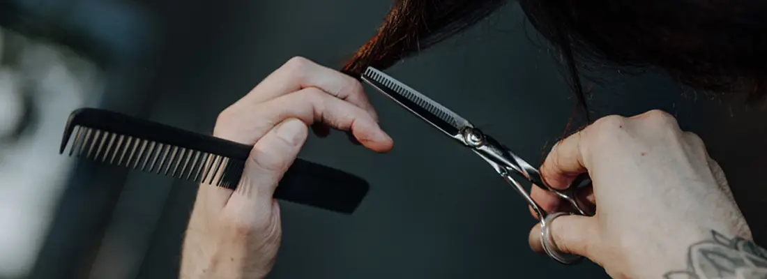 Detailaufnahme Haarschnitt: Hände mit Kamm und Effilierschere schneiden eine Haarsträhne – Friseursalon Marco Stauber, Röthenbach an der Pegnitz.