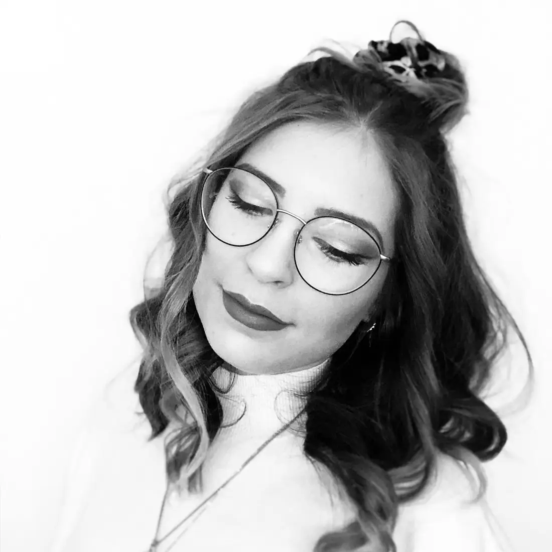 Portrait von Sophie mit runder Brille und welligem Haar, Blick nach unten – Team Friseur Marco Stauber.